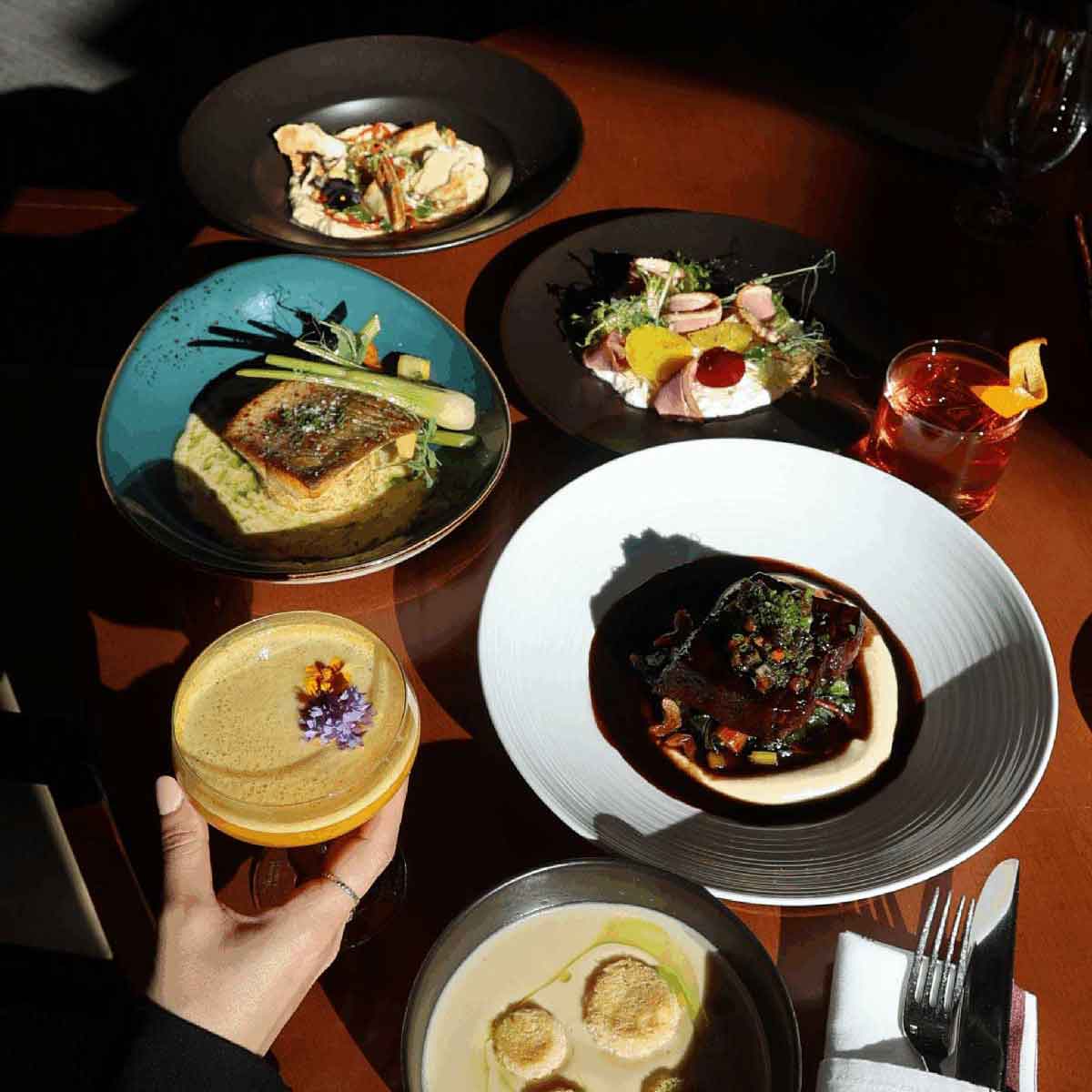 Gazettte Bistro Bar table with multiple dishes and a drink